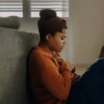 Woman leaning against couch showing anxiety