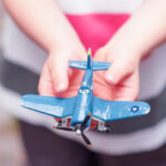 Child holding toy airplane in their hands